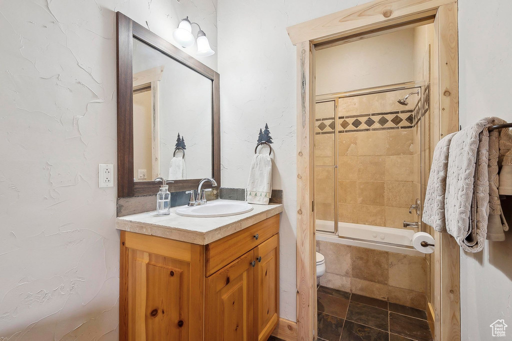 Full bath featuring vanity, tiled shower / bath, and toilet