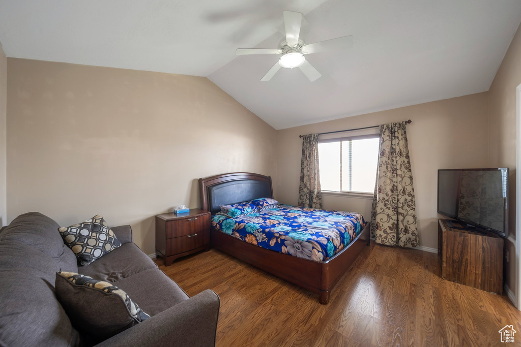 Bedroom with vaulted ceiling, wood finished floors, ceiling fan, and baseboards