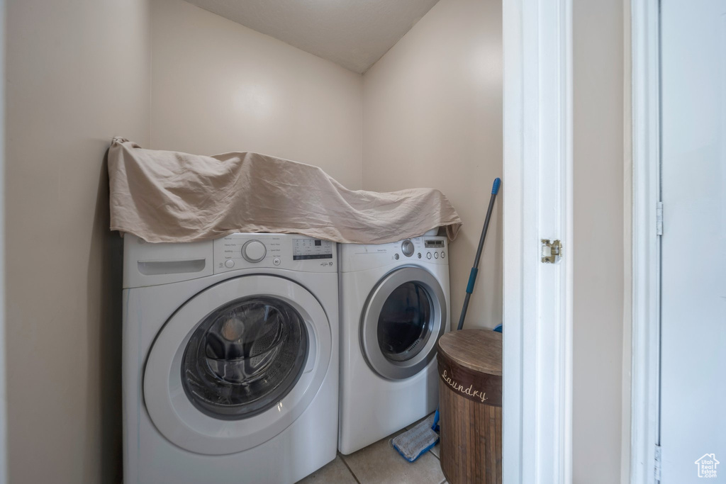 Washroom featuring washing machine and clothes dryer and light tile patterned floors