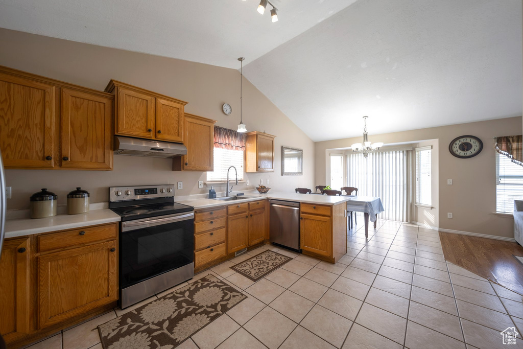 Kitchen featuring stainless steel appliances, under cabinet range hood, a peninsula, lofted ceiling, and light countertops