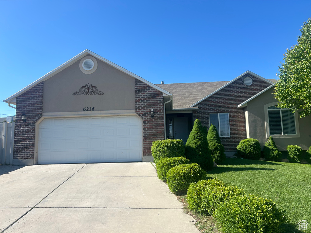 Ranch-style house with brick siding, concrete driveway, a garage, and a front yard