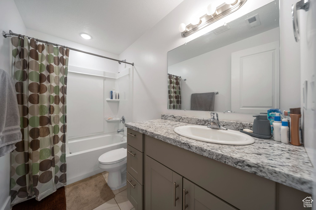 Bathroom with vanity, shower / bath combo, toilet, and tile patterned flooring