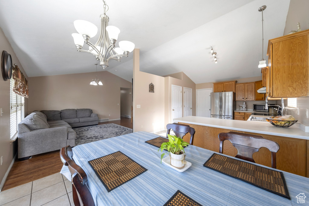Dining area with vaulted ceiling, a chandelier, light tile patterned flooring, and baseboards