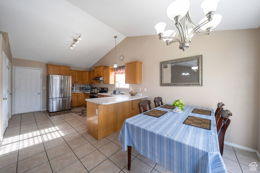 Kitchen featuring appliances with stainless steel finishes, a peninsula, under cabinet range hood, a sink, and light countertops