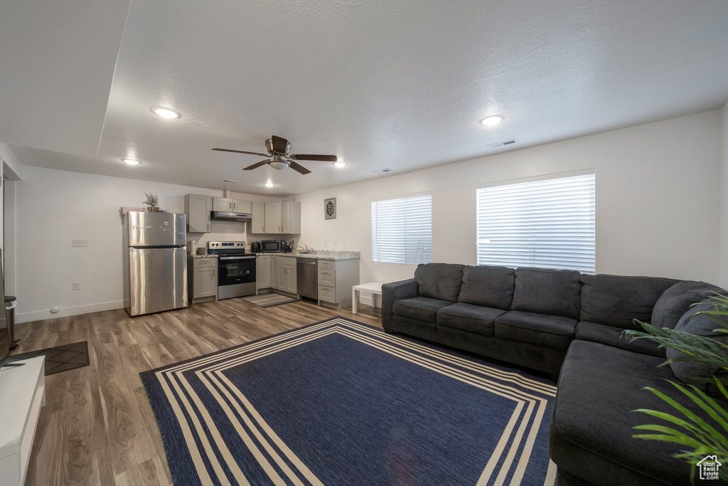 Living area with wood finished floors, a ceiling fan, recessed lighting, and baseboards