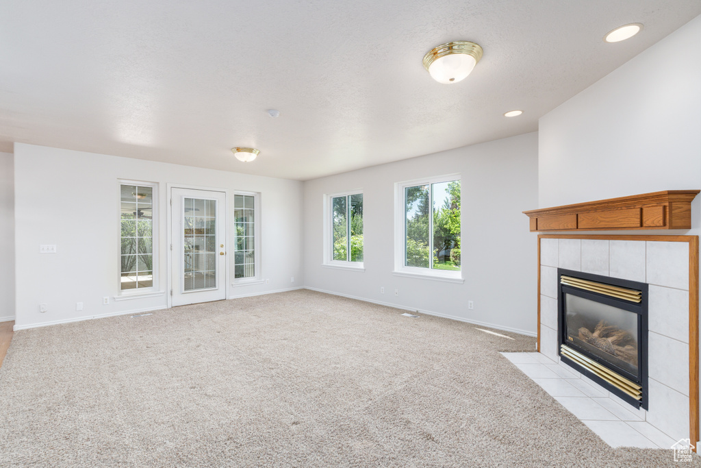 Unfurnished living room featuring a fireplace, baseboards, light colored carpet, and recessed lighting