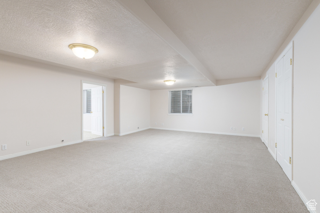 Unfurnished bedroom with light carpet, baseboards, and a textured ceiling