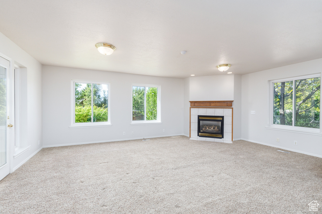 Unfurnished living room featuring light colored carpet, a fireplace, and baseboards