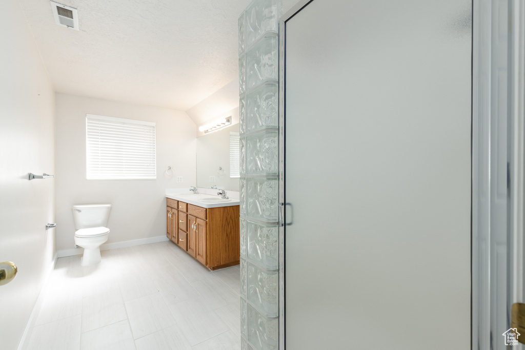 Full bathroom with toilet, a shower stall, baseboards, and double vanity