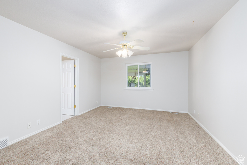 Empty room featuring carpet floors, a ceiling fan, and baseboards