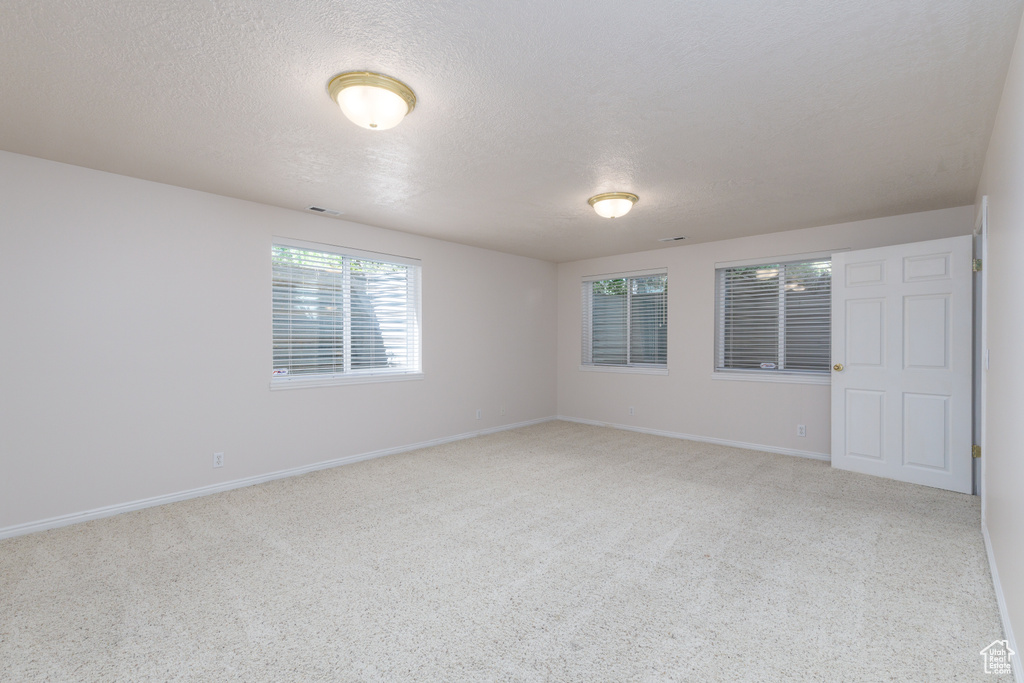 Unfurnished room with light colored carpet, a textured ceiling, and baseboards