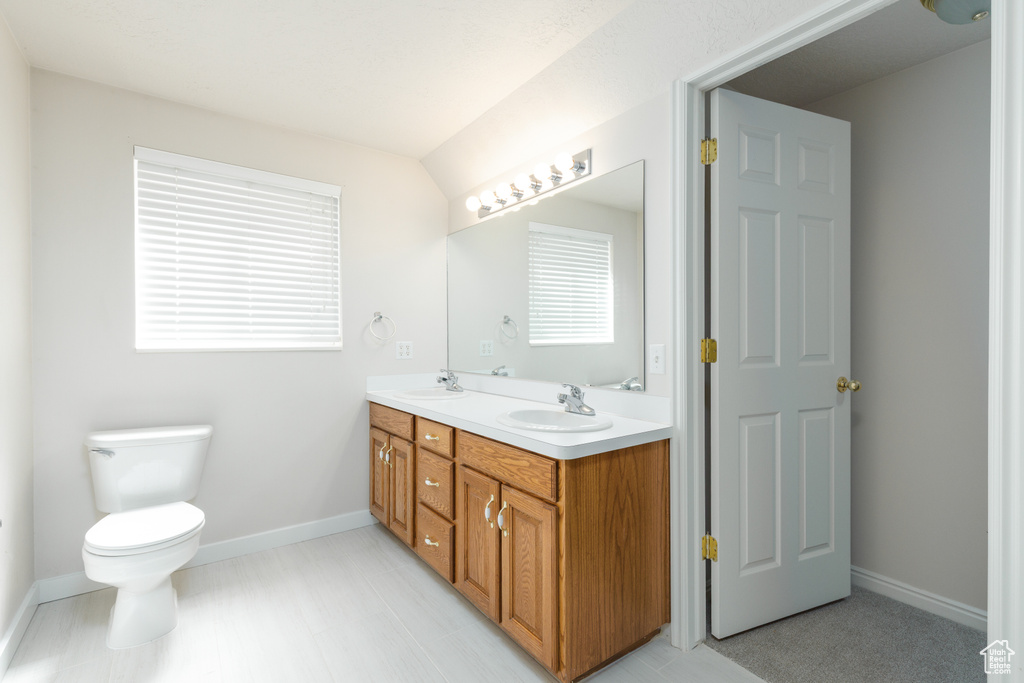 Bathroom featuring toilet, baseboards, and double vanity