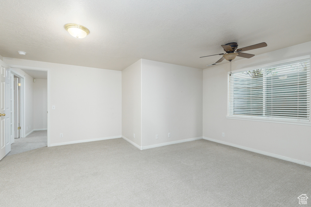 Spare room featuring a ceiling fan, light colored carpet, and baseboards
