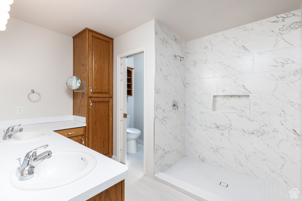 Full bathroom featuring a shower stall, double vanity, and toilet