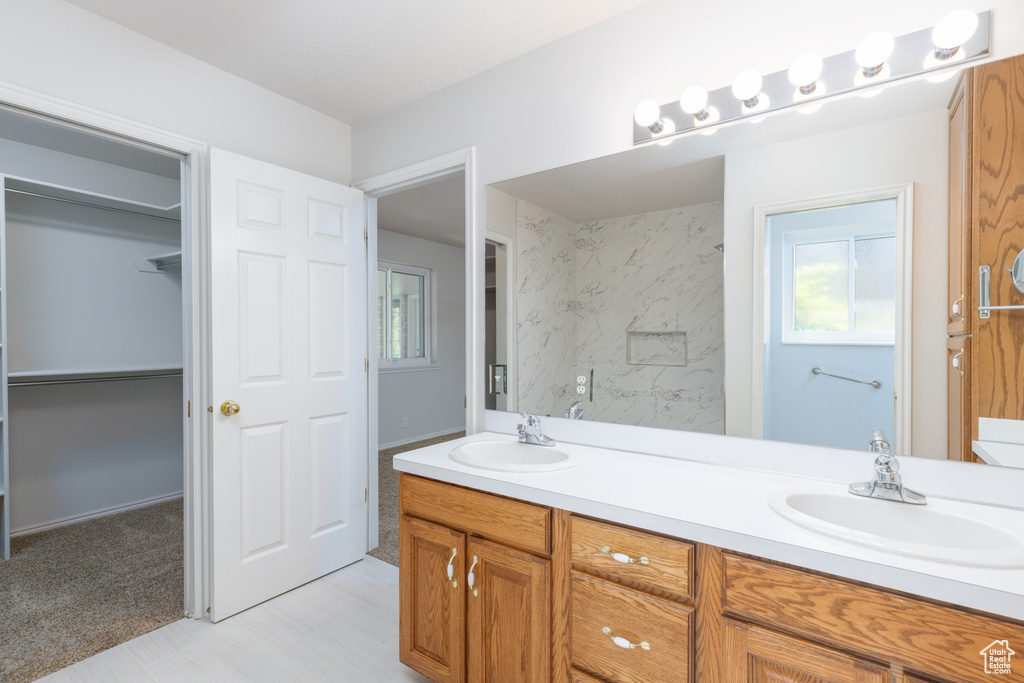 Full bathroom featuring double vanity and a spacious closet