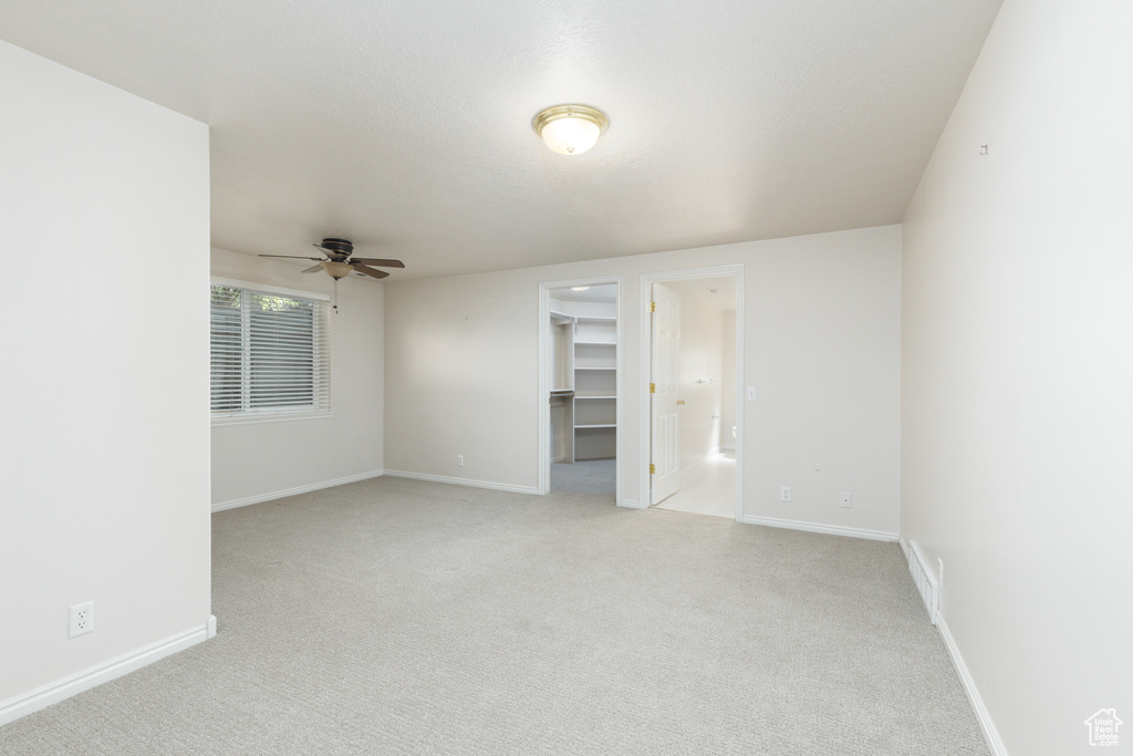 Spare room featuring ceiling fan, light carpet, and baseboards