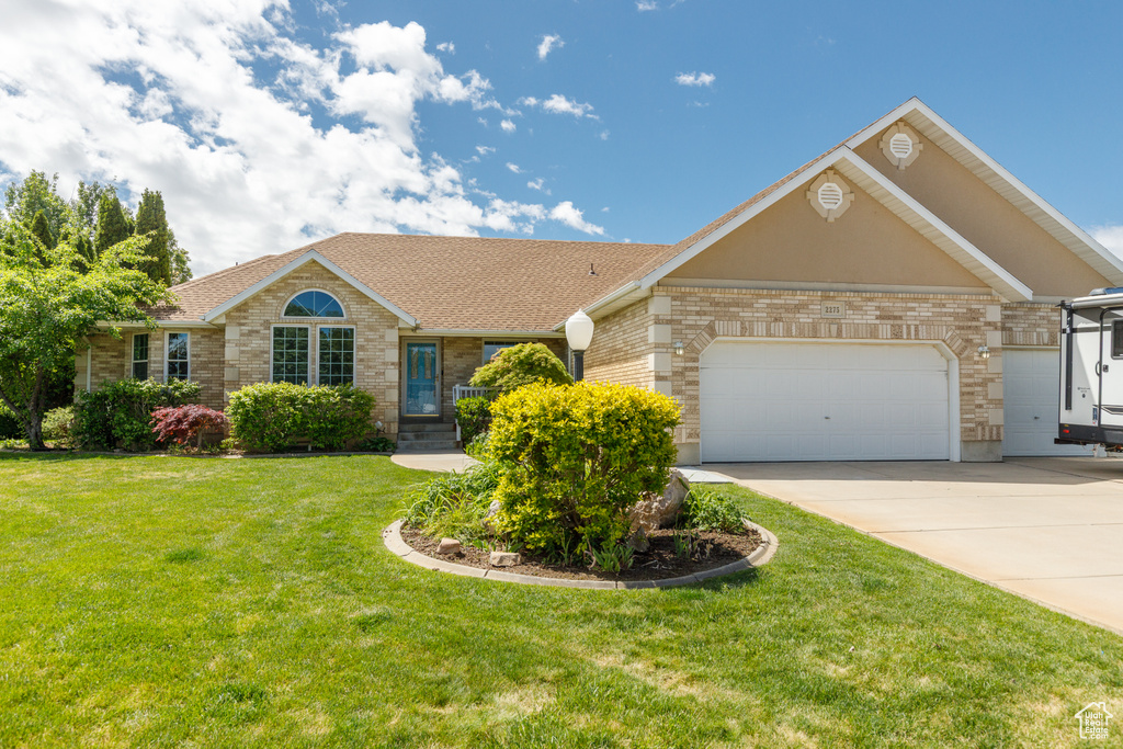 Ranch-style home with a front lawn, an attached garage, brick siding, concrete driveway, and a shingled roof