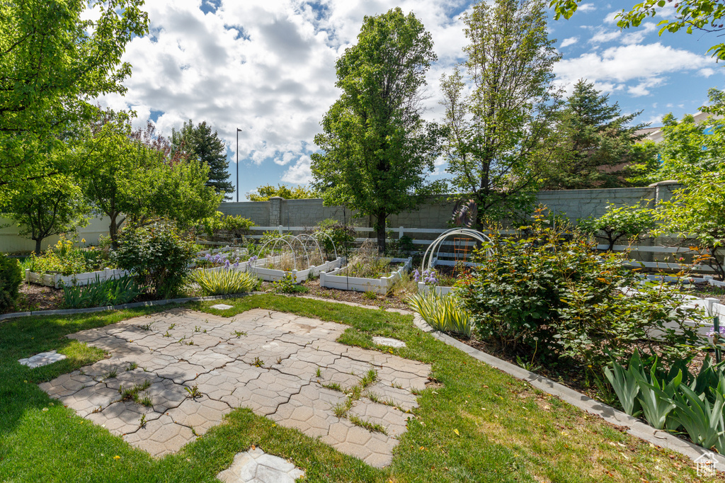 Fenced backyard with a vegetable garden and a patio area