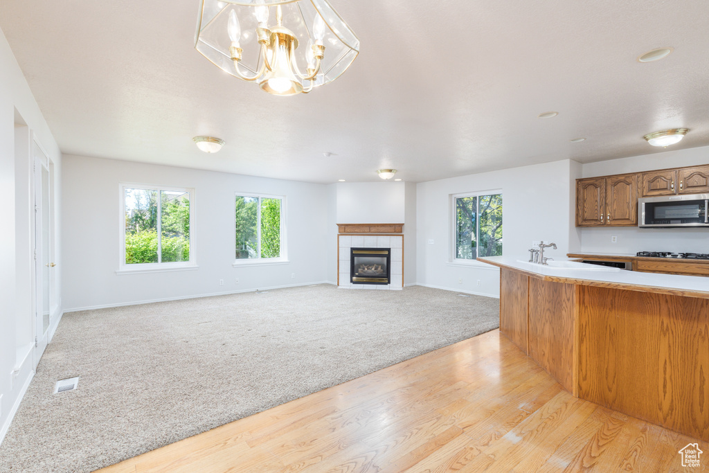 Kitchen with stainless steel microwave, light colored carpet, a sink, gas cooktop, and baseboards