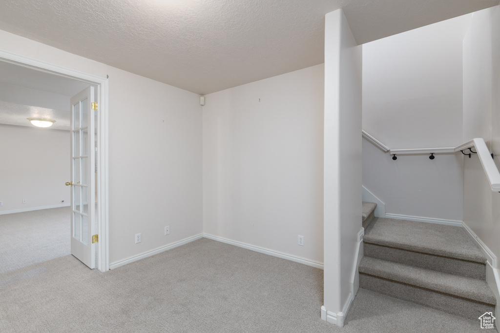 Stairway featuring carpet, a textured ceiling, and baseboards