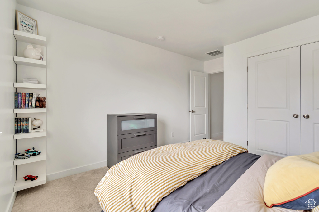 Bedroom with light carpet, baseboards, and a closet