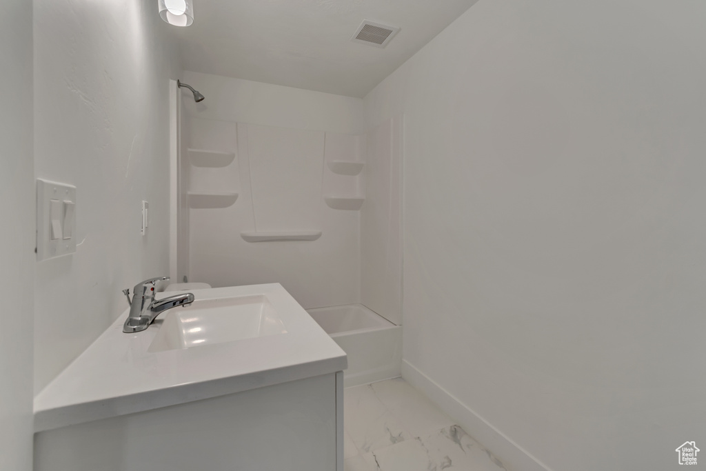 Full bath featuring marble finish floors, baseboards,  shower combination, and vanity