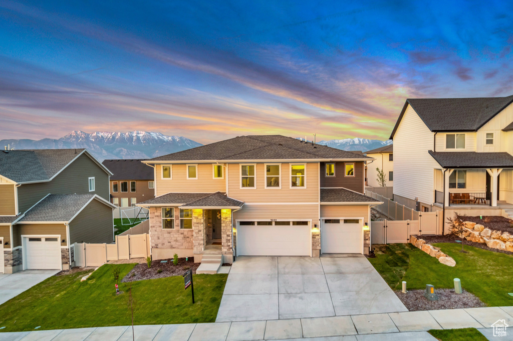 View of front of home featuring a gate, a garage, driveway, stone siding, and a mountain view