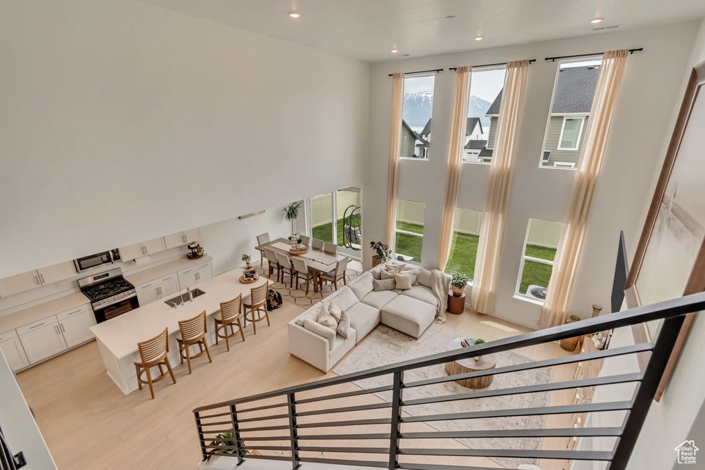 Living room with light wood-style floors, recessed lighting, and a towering ceiling