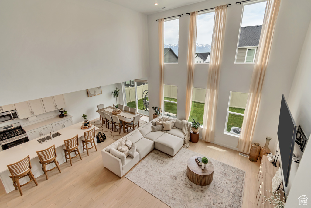 Living room with a towering ceiling, light wood finished floors, and healthy amount of natural light