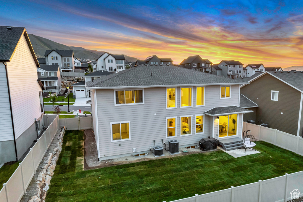 Back of house with a residential view, central AC unit, and roof with shingles