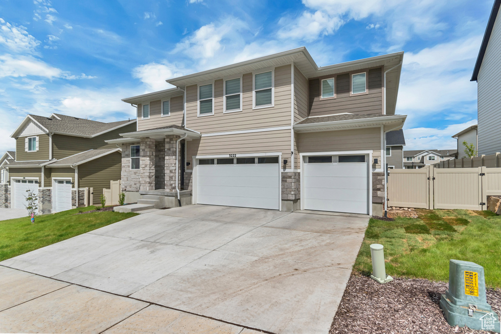 Prairie-style house with a gate, an attached garage, concrete driveway, and stone siding