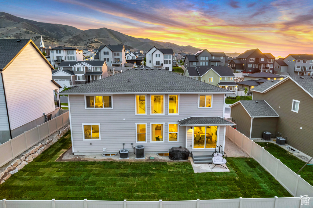 Back of property at dusk with a residential view, a mountain view, a patio area, and a shingled roof