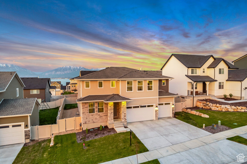 View of front of home featuring concrete driveway, an attached garage, a mountain view, a residential view, and stone siding