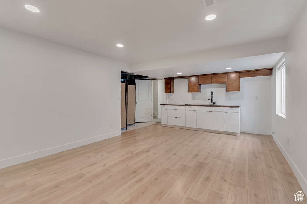 Unfurnished living room featuring a sink, light wood finished floors, recessed lighting, and baseboards