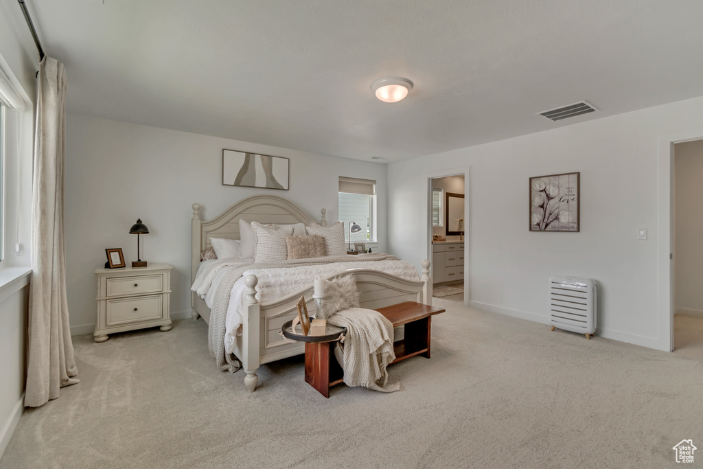 Bedroom with light colored carpet, baseboards, and connected bathroom