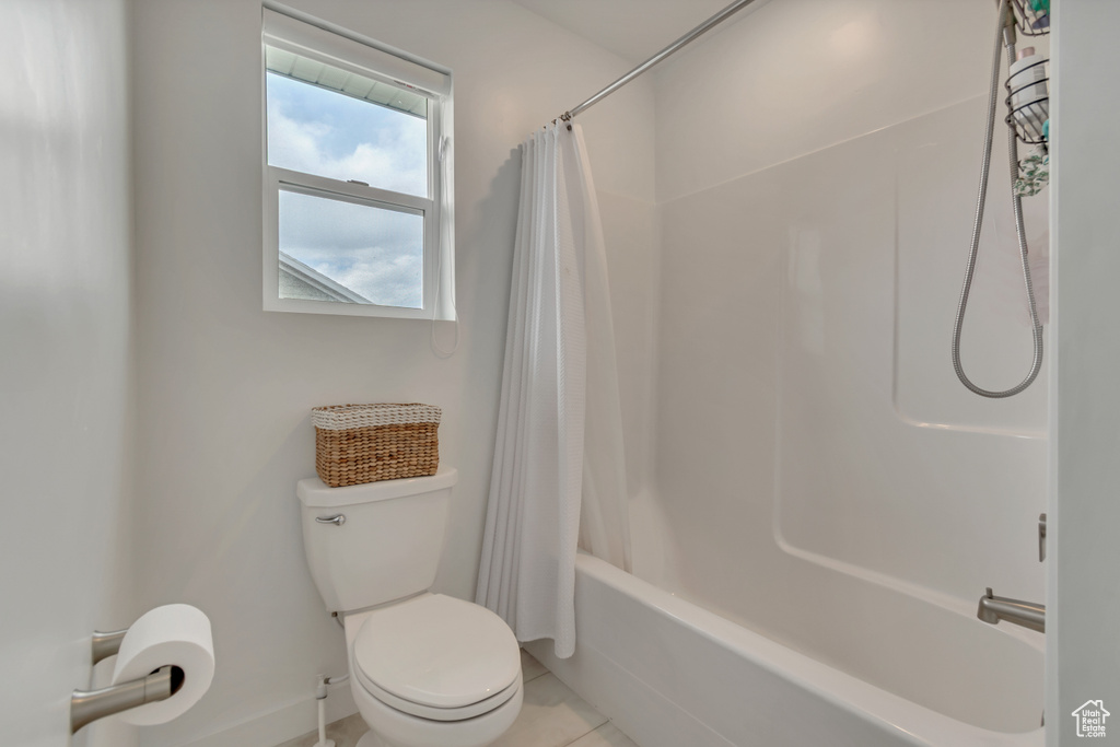 Bathroom with toilet, shower / bath combo with shower curtain, and tile patterned floors