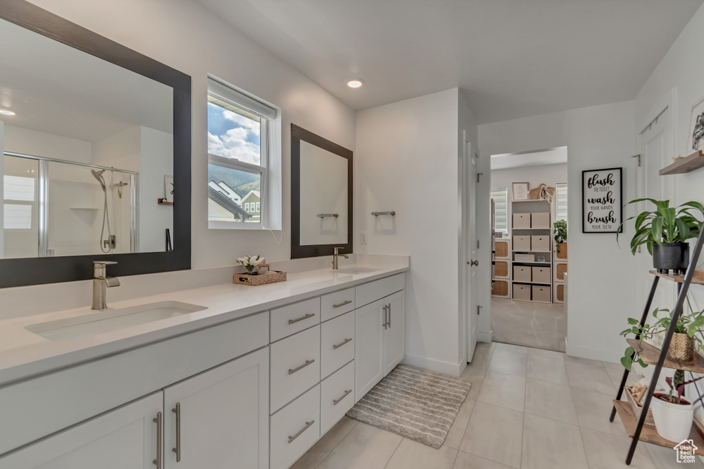 Bathroom with a stall shower, double vanity, tile patterned floors, baseboards, and recessed lighting