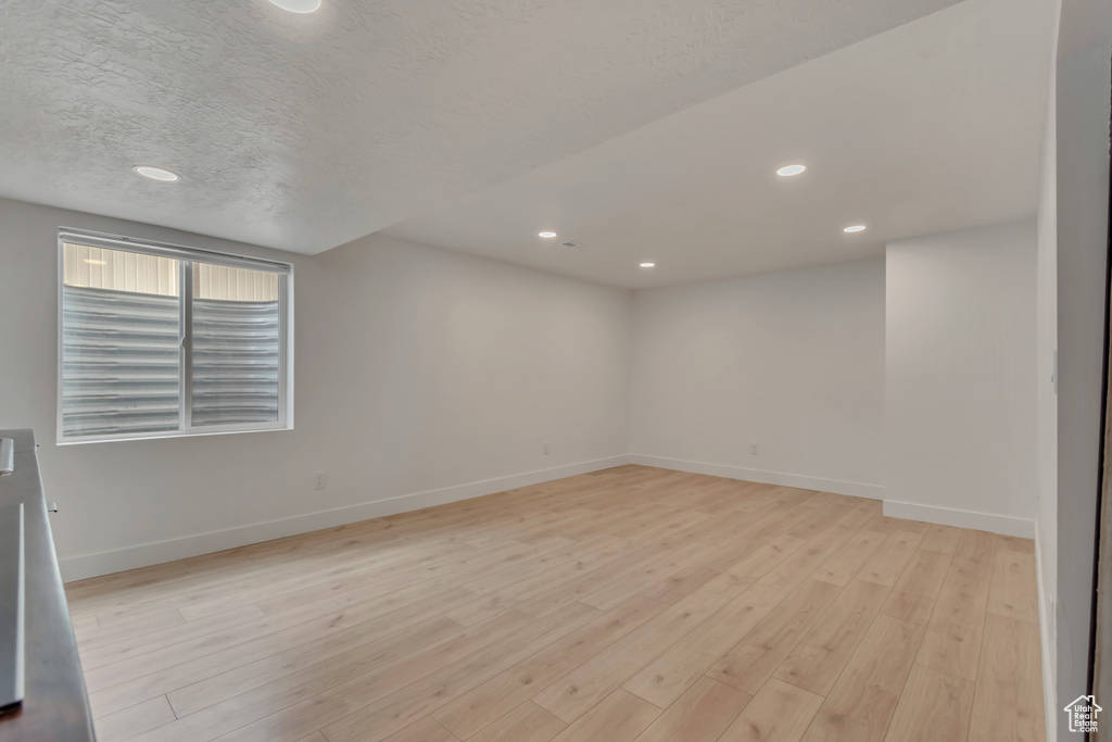 Empty room with baseboards, light wood finished floors, recessed lighting, and a textured ceiling