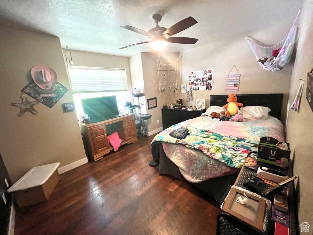 Bedroom with dark wood-type flooring, baseboards, and ceiling fan