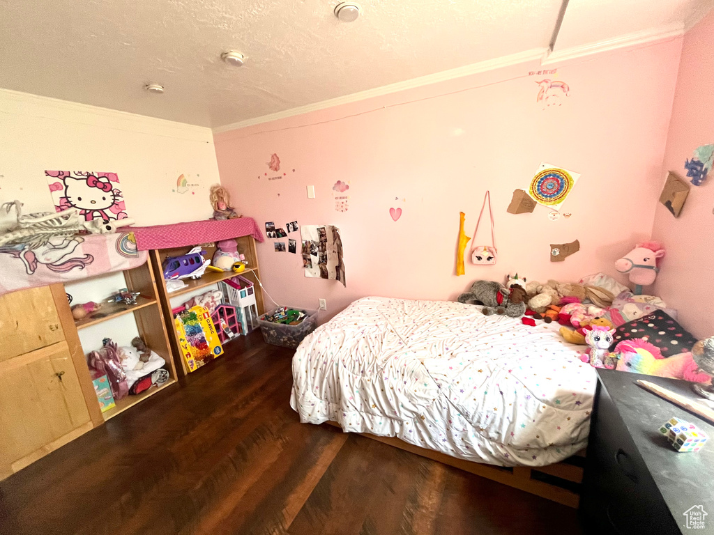 Bedroom with ornamental molding, wood finished floors, and a textured ceiling