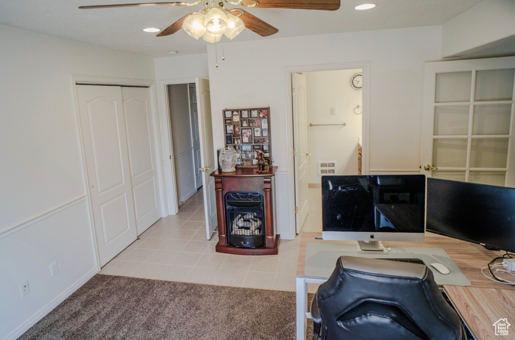 Office featuring ceiling fan, a wood stove, light tile patterned floors, recessed lighting, and light colored carpet