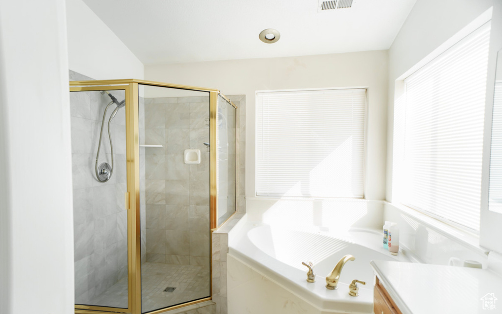 Full bathroom featuring plenty of natural light, a garden tub, a shower stall, and vanity