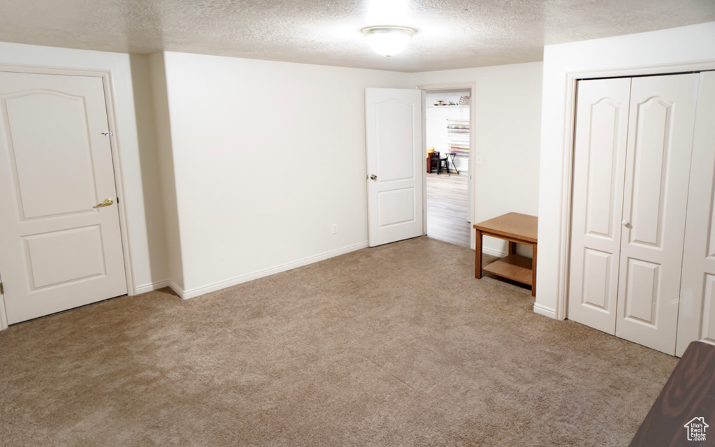 Unfurnished bedroom with a textured ceiling, carpet, a closet, and baseboards