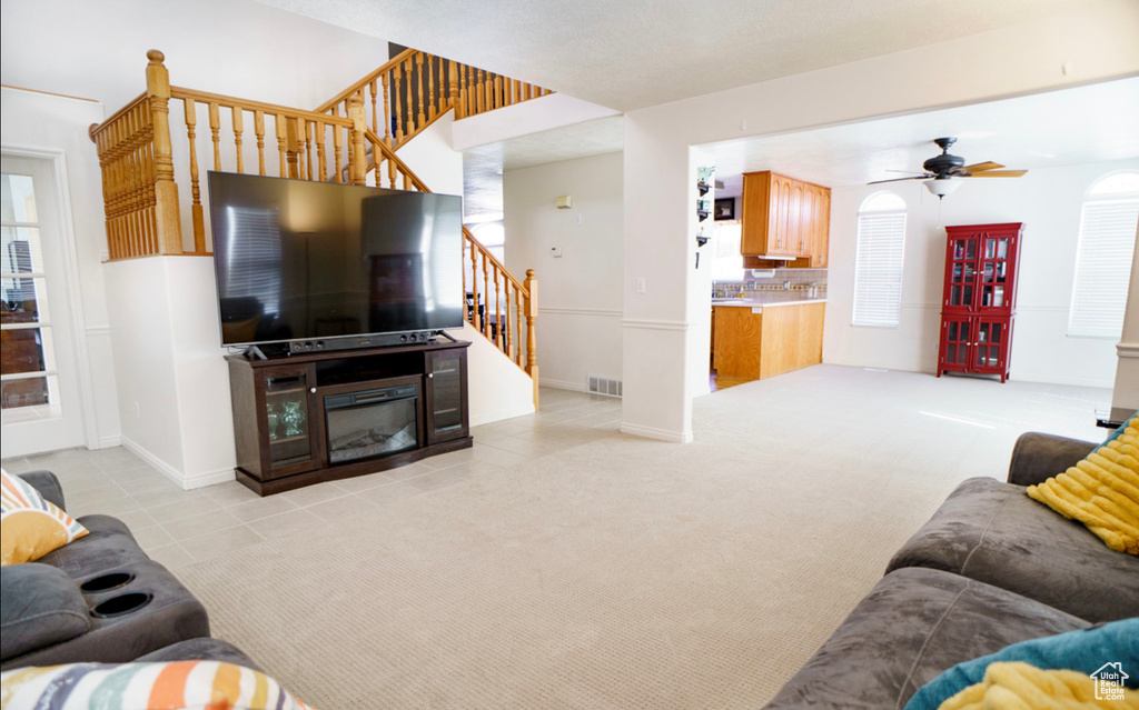 Living room with stairs, a ceiling fan, light tile patterned floors, and baseboards