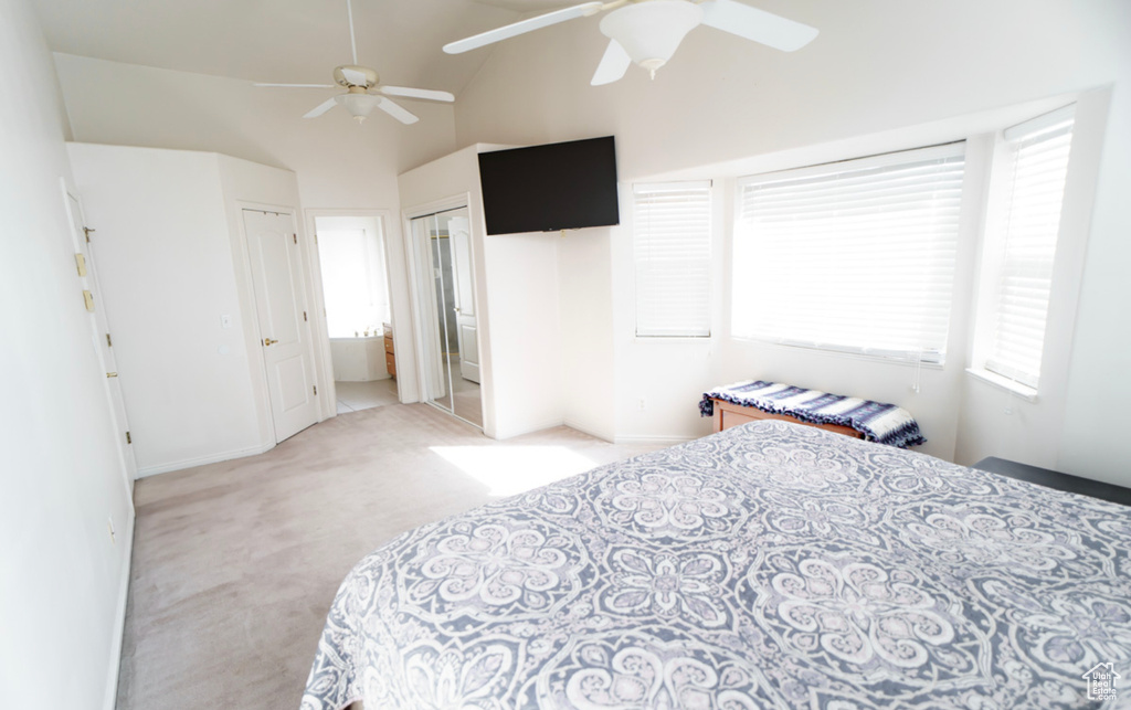 Bedroom with light carpet, vaulted ceiling, a ceiling fan, baseboards, and a closet