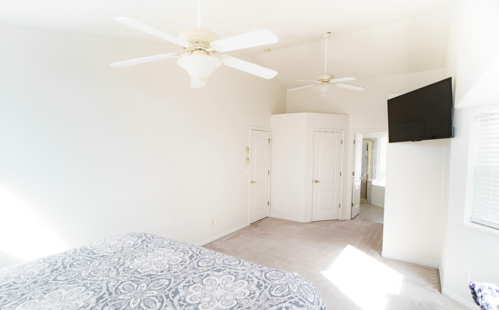 Unfurnished bedroom featuring carpet, baseboards, high vaulted ceiling, and ceiling fan