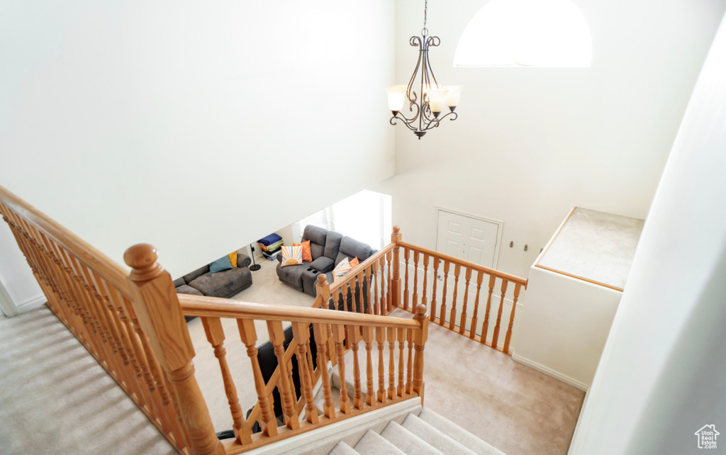 Stairs featuring carpet floors, baseboards, a chandelier, and a towering ceiling