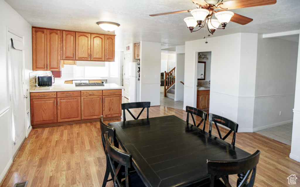 Dining space with a ceiling fan, light wood-style flooring, stairs, and baseboards