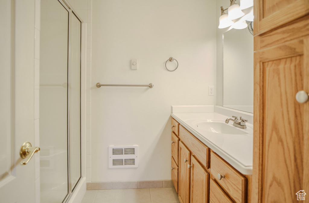 Full bath featuring a shower with shower door, tile patterned floors, vanity, and baseboards