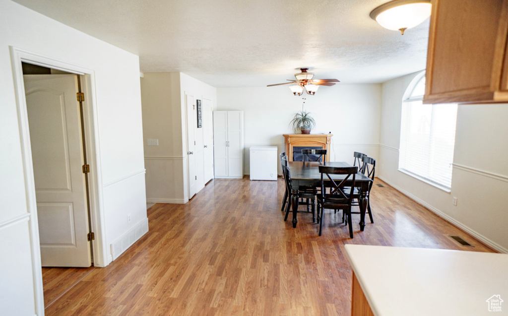Dining room featuring ceiling fan, light wood-type flooring, baseboards, and a fireplace